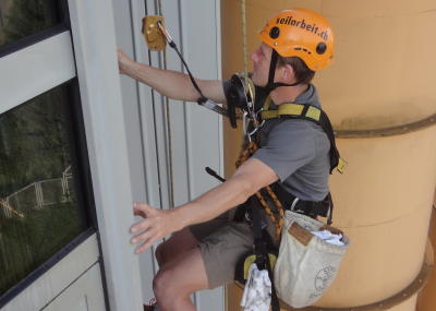 Industriekletterer bei Glasreinigung am hängenden Seil, Arbeit am Seil in der Höhe