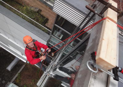 Fassadenkletterer reinigt Glasfront am hängenden Seil, Seilarbeit