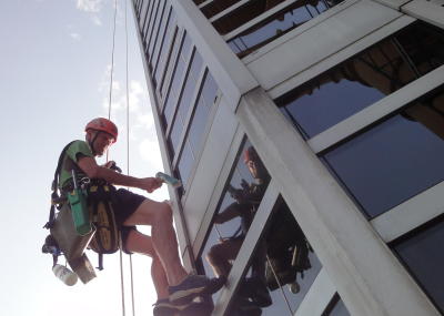 Industriekletterer bei Glasreinigung am hängenden Seil, Arbeit am Seil in der Höhe
