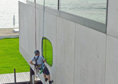 Glasreinigung am Seil in der Höhe, Gebäudereinigung mit Fassadenkletterer und Arbeit am Seil