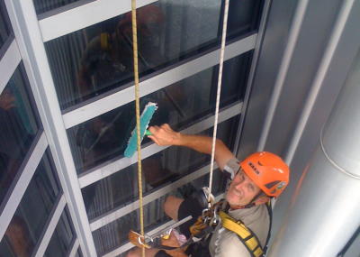Industriekletterer bei Glasreinigung am hängenden Seil, Arbeit in der Höhe